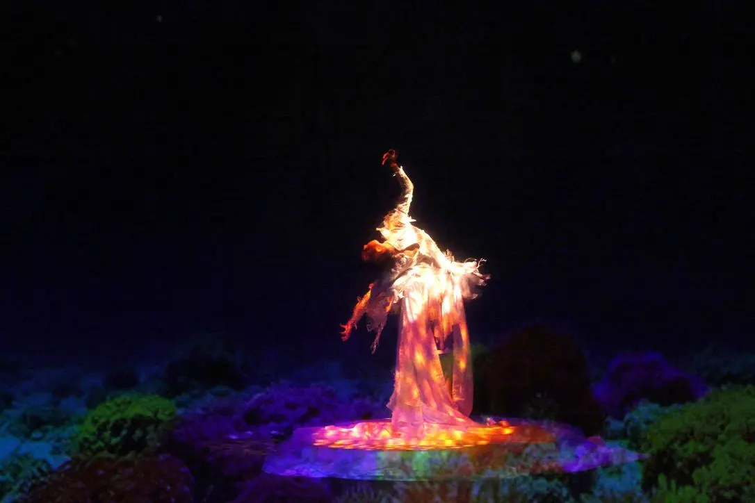 Danseuse en robe lumineuse sur une scène de coraux colorés